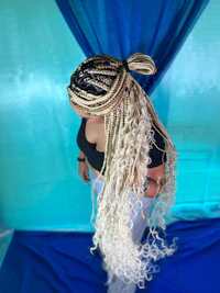 a woman with long braided hair in front of a blue curtain