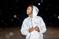 a man in a white hoodie standing in the snow