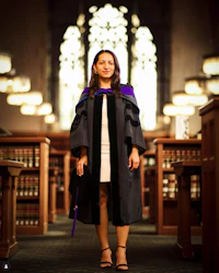 a woman in a graduation gown standing in a library