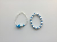 two blue and white beaded bracelets on a white surface