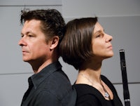 a man and woman standing next to each other holding a flute