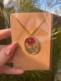 a person holding a necklace with a flower on it