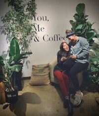 two women sitting in front of a sign that says you me & coffee