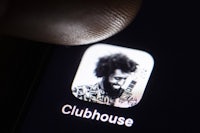 a person is pointing at the clubhouse app on an iphone