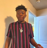 a young man in a striped shirt standing in front of a door