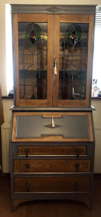 a wooden desk with glass doors and drawers