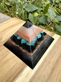 a pyramid made of black and blue stones on a wooden table