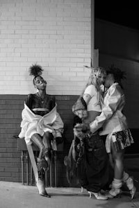 a black and white photo of a group of people leaning against a wall