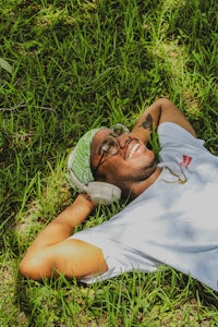 a man laying in the grass with headphones on