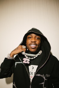 a man in a black hoodie holding a necklace