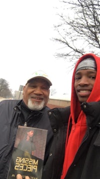 two men standing next to each other holding a book