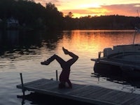 a person doing a handstand on a dock at sunset