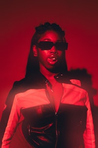 a woman in sunglasses standing in front of a red light