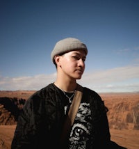 a young man in a beanie standing in a desert