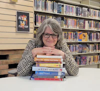 Woman resting her head on stack of books.