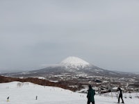 a group of people standing on a snowy slope with a mountain in the background