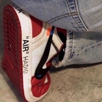 a person's feet are sitting on a pair of sneakers