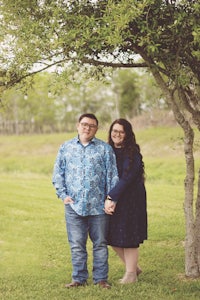 a couple standing under a tree in a field