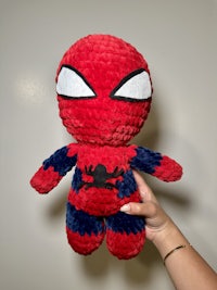 a person holding a spider - man plush toy