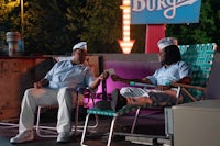 two men sitting on lawn chairs in front of a burger king sign