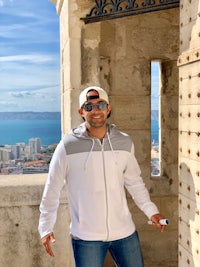 a man in a white hoodie standing in front of a castle