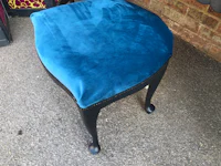 a blue velvet stool with a black base