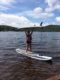 a woman standing on a surfboard holding a surfboard