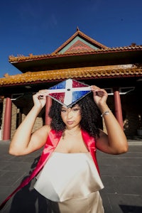 a woman wearing a graduation hat in front of an asian building