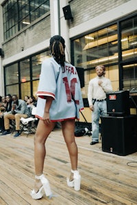 a woman in a baseball jersey standing in front of a crowd