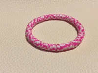 a pink and white striped bracelet on a white surface