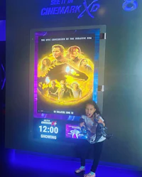 a young girl standing in front of a movie poster