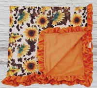 a baby blanket with sunflowers and orange ruffles