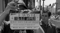 a man takes a picture of a man holding a clapper board