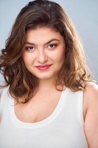 a woman in a white tank top posing for a photo