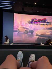 a person's feet are on the floor in front of a large screen