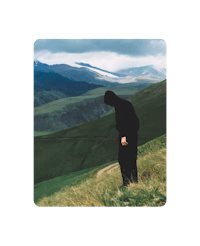 a man in a black hoodie standing on top of a hill