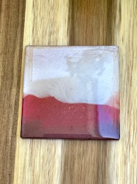 a red and white glass coaster on a wooden table