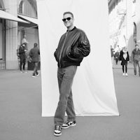 a black and white photo of a man posing in front of a wall