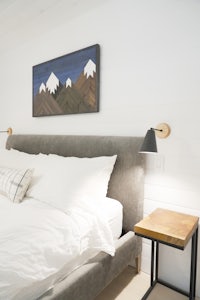 a bed in a bedroom with a painting on the wall