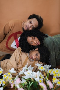 three people posing with flowers in front of them