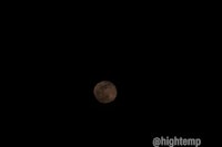 a full moon rising over a dark sky