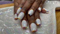 a woman is holding a white plate with colorful nails