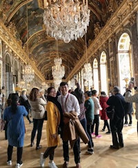 a couple posing in an ornate room with chandeliers