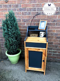 a small black cabinet next to a potted plant