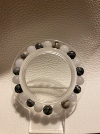 a clear glass holder with black and white beads