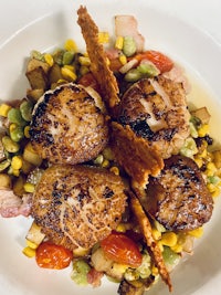 scallops with corn and vegetables on a white plate