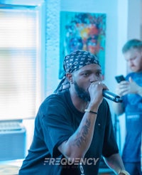 a man in a bandana is singing into a microphone