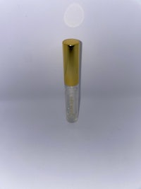 a gold bottle with a gold cap on a white surface