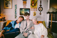 three people sitting on a couch in a living room