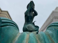 a statue of a mermaid sitting on top of a building